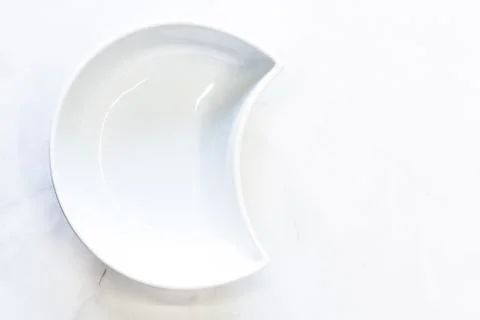 White bowl in the shape of a half-moon. Top view, space for text. Stock Photos