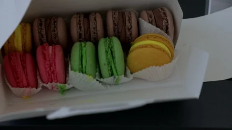 A white box with beautiful macarons in green, pink, beige, brown, and yellow Stock Footage 322183643