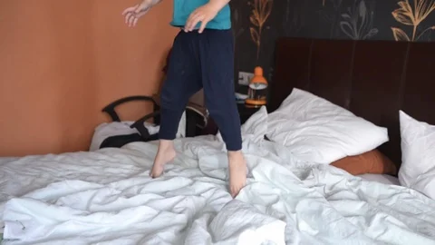 White boy 4 years old jumping on a large white double bed steadicam shot Stock Footage 124315414