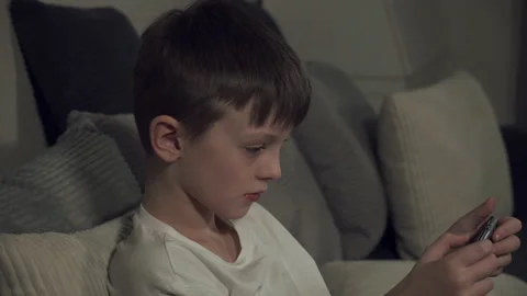 White boy 8 years old on the couch. The boy is enthusiastically playing a game o Stock Footage 146316641