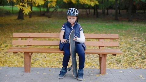 White boy with broken arm sitting with skate Stock Footage 83993475