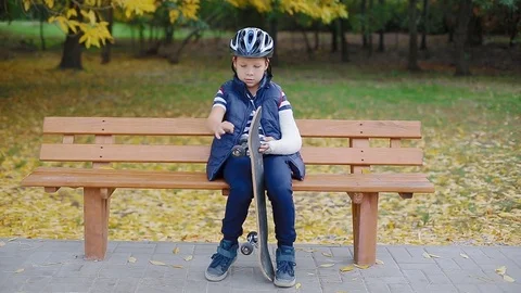 White boy with broken arm sitting with skate Stock Footage 83993527
