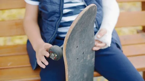 White boy with broken arm sitting with skate Stock Footage 83993636