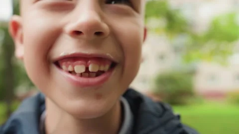 White boy closeup eating ice cream cone near school, animated missing tooth grin Stock Footage 333102848