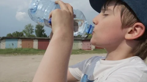 Teen boy drinking water outdoors Stock Video Footage by ©VaLiza #199836560