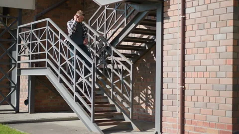 White boy placing cigarette while descending metal staircase Stock Footage 307051291