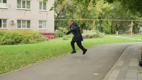 White boy running toward school path, autumn park, backpack on bench, brisk Stock Footage 338288189