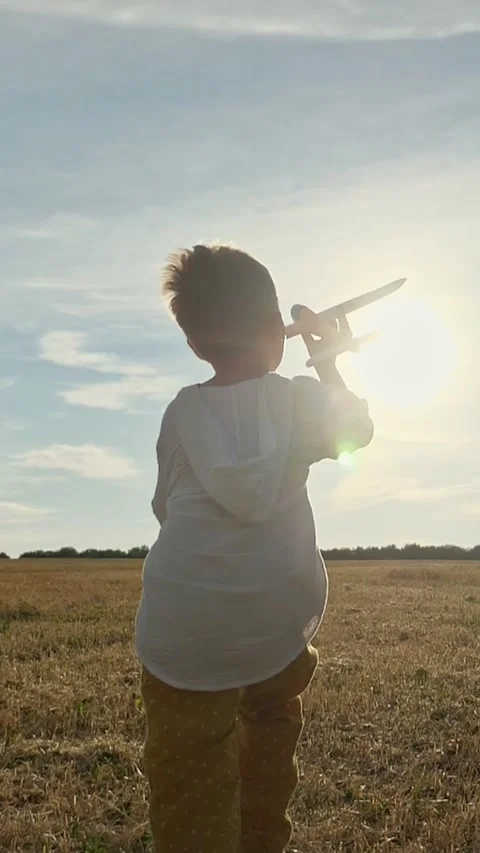 White Boy Running With Toy Airplane Toward Sunset Across Open Field. Child 库存影片 334886845