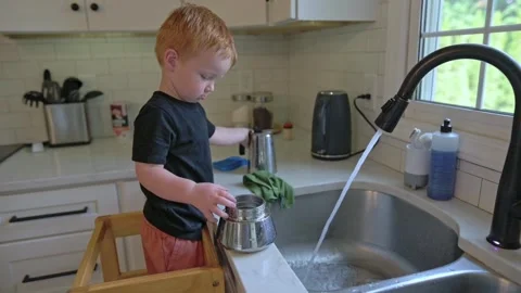 White boy washes pot at sink with focus and curiosity, small redhead child Vídeo Stock 323095308