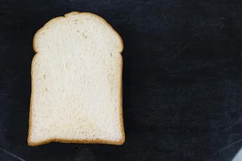 White bread slice isolated on black wood background Stock Photos