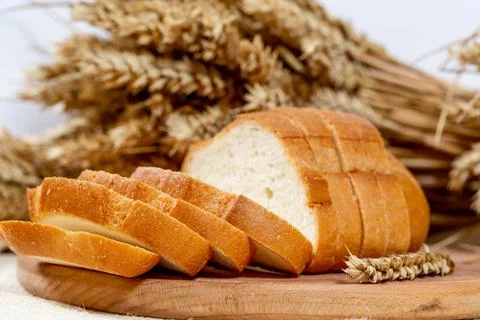 White bread sliced on a kitchen Board with wheat spikelets Stock Photos