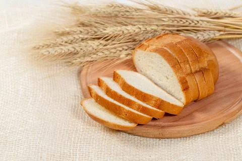 White bread sliced on a kitchen Board with wheat spikelets Stock Photos