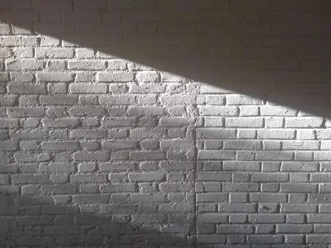 White brick wall, with diagonal ray of sunlight forming contrast of light and Foto stock