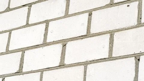 A white brick wall with a few bricks missing Stock Photos