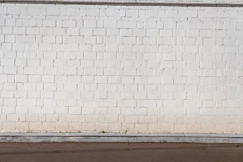 White brick wall texture with horizontal lines and street pavement background Foto stock