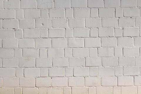 White brick wall texture with uneven surface and shadows Stock Photos