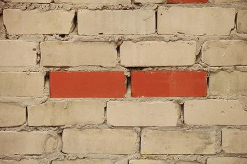 White brick wall with two red bricks in the middle Stock Photos