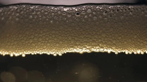 White bubbles floating on a liquid cider. Video stock 89309500