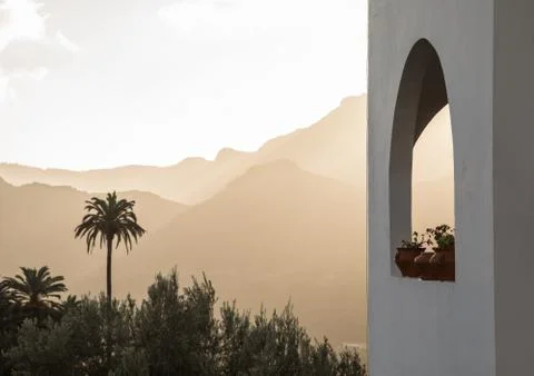 White building with arch window with plants, palm trees and mountains in the Stock Photos