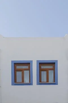 A white building with blue window frames against a blue sky in the Greek style Stock Photos