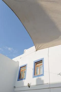 A white building with blue window frames against a blue sky in the Greek style Stock Photos