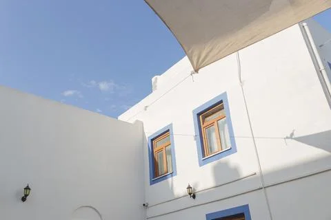 A white building with blue window frames against a blue sky in the Greek style Stock Photos