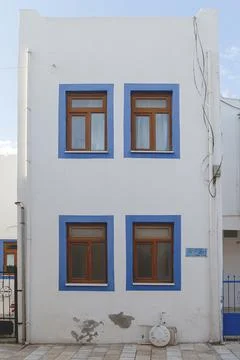 A white building with blue window frames against a blue sky in the Greek style Stock Photos