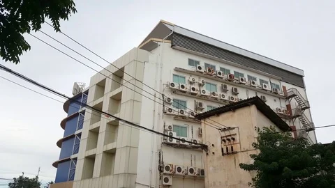 White building covered with air conditioning units, leaves, Vientiane, Laos Видео 75238912