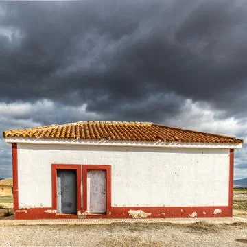 White building with red frames on its corners under a sky full of clouds Stock Photos