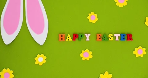 White bunny ears, small flowers on a green background and text Happy Easter Stock Footage 331505428