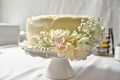 White Buttercream Wedding Cake on Stand Decorated With Hydrangeas and Babys Stock Photos