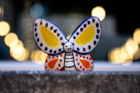 White butterfly, made of glazed ceramic, colored with yellow, orange, and blue Foto stock