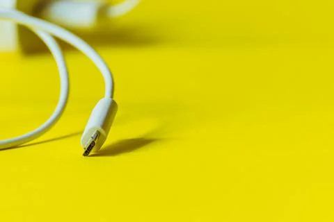 White cable with micro usb plug on a yellow background. Stock Photos