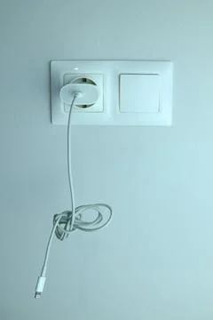 White cable plugged into wall socket Stock Photos