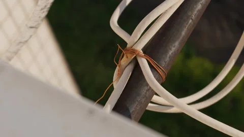White Cable Tied to Rusty Metal Pole with Thin Copper Wire Stock Footage 334132071