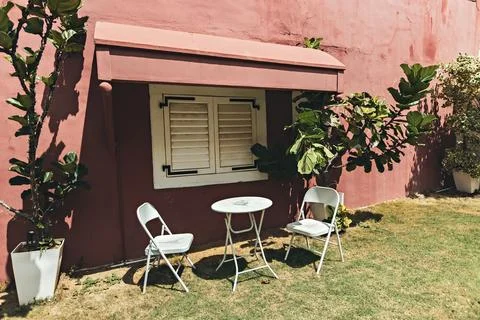 White cafe table and chairs in front of the red wall in the garden Stock Photos