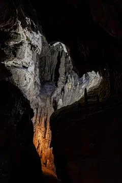 White calcite column emerging from darkness under directional lighting in a.. Stock Photos