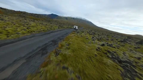 A white camper is driving along a remote road surrounded by a mossy and rock Stock Footage 226370480