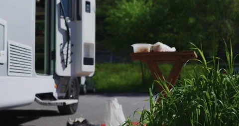White camper sits parked with its door open next to a tiny wooden table and Video stock 324891727