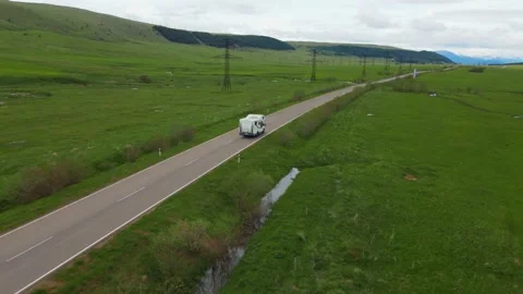 White camper van driving on scenic countryside road Vídeos de archivo 343305434