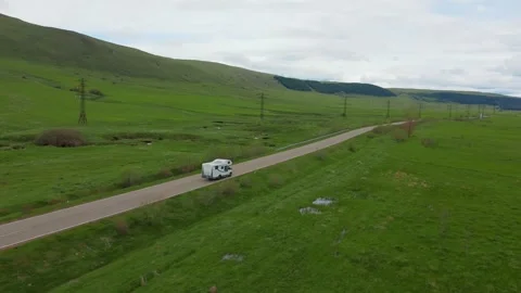 White camper van driving through green countryside landscape Stock Footage 345963073