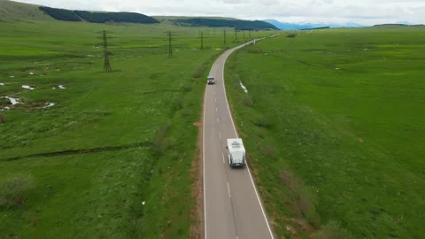 White camper van driving through green countryside landscape Stock Footage 346610743