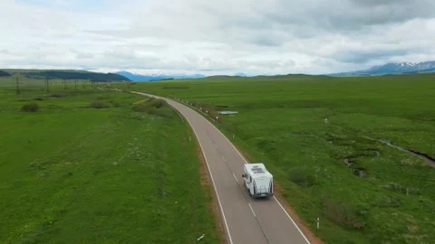 White camper van driving through green countryside landscape Stock Footage 346610988