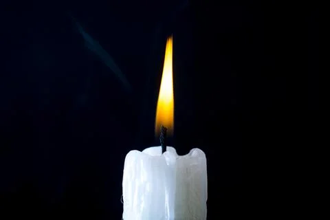 White candle burning on a black background Stock Photos