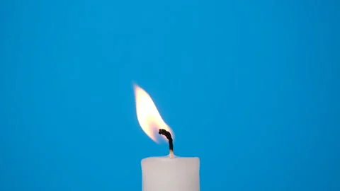A white candle burning on a blue background. A candle is blown out, beautiful Stock Footage 230107468