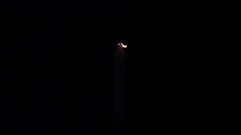 White Candle Burning in the Dark with lights glow. One Candle flame lights. Stock Footage 263015466
