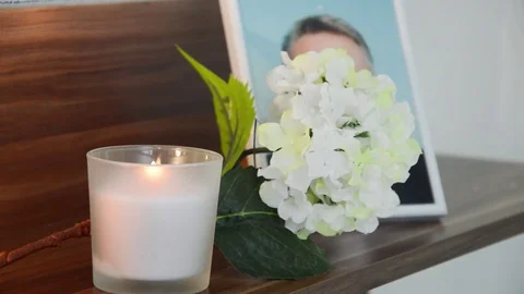 White candle burning in the front the image of the deceased. Stock Footage 70198345