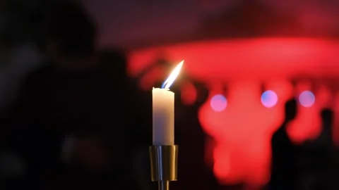 White candle burning on metallic holder in purple-lit banquet hall Video stock 342018370