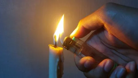 A white candle that burns in the dark to light up the room Stock Photos