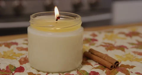 White candle lit in kitchen with cinnamon sticks daytime closeup Stock Footage 249287951